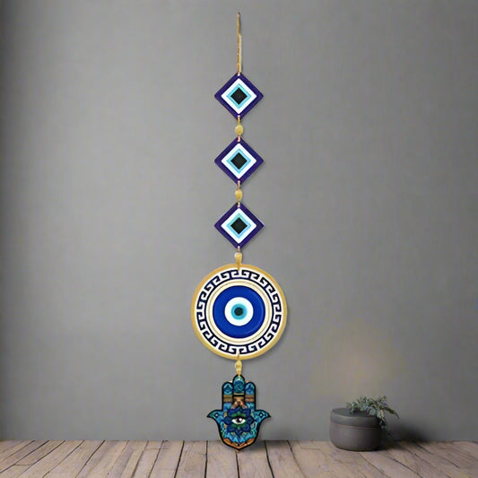 Decorative wall hanging with eye design and Hamsa hand on a white brick wall.