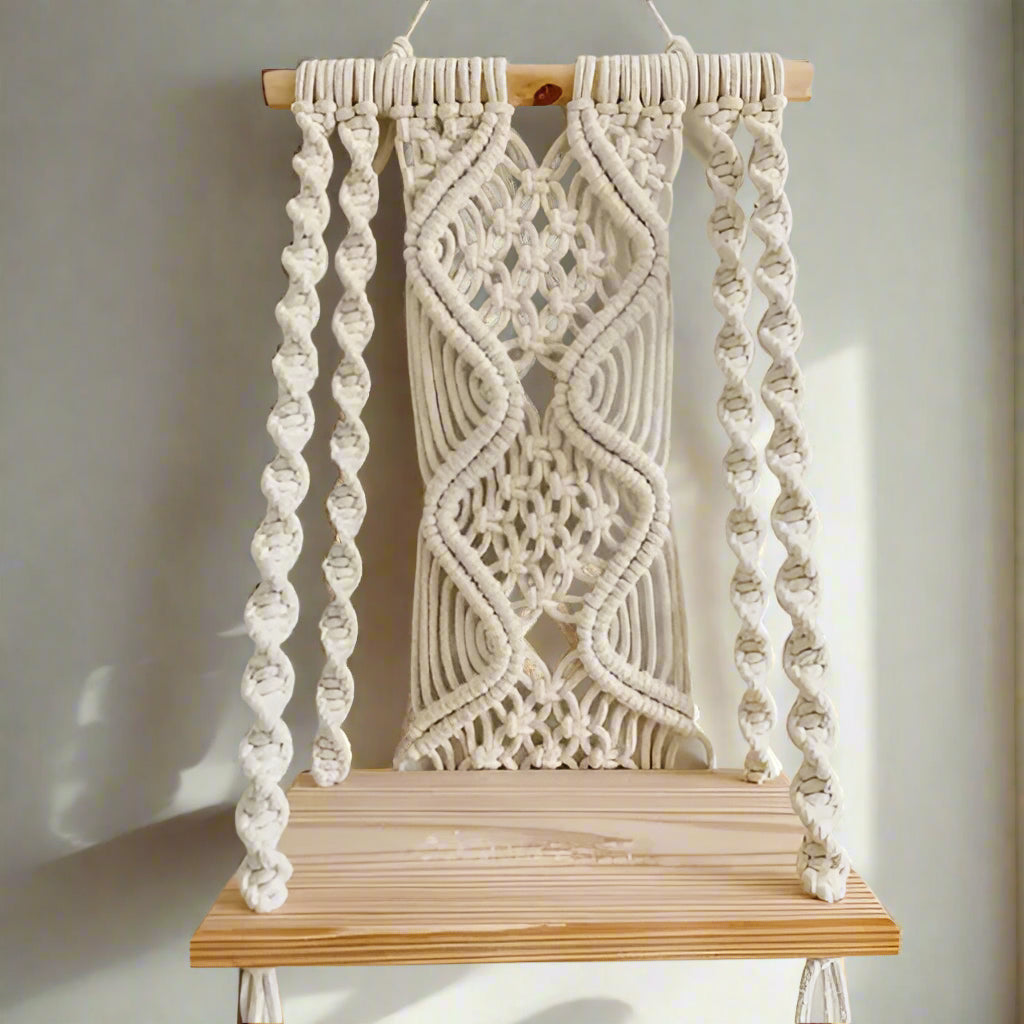 Macrame wall hanging with wooden base on a plain background